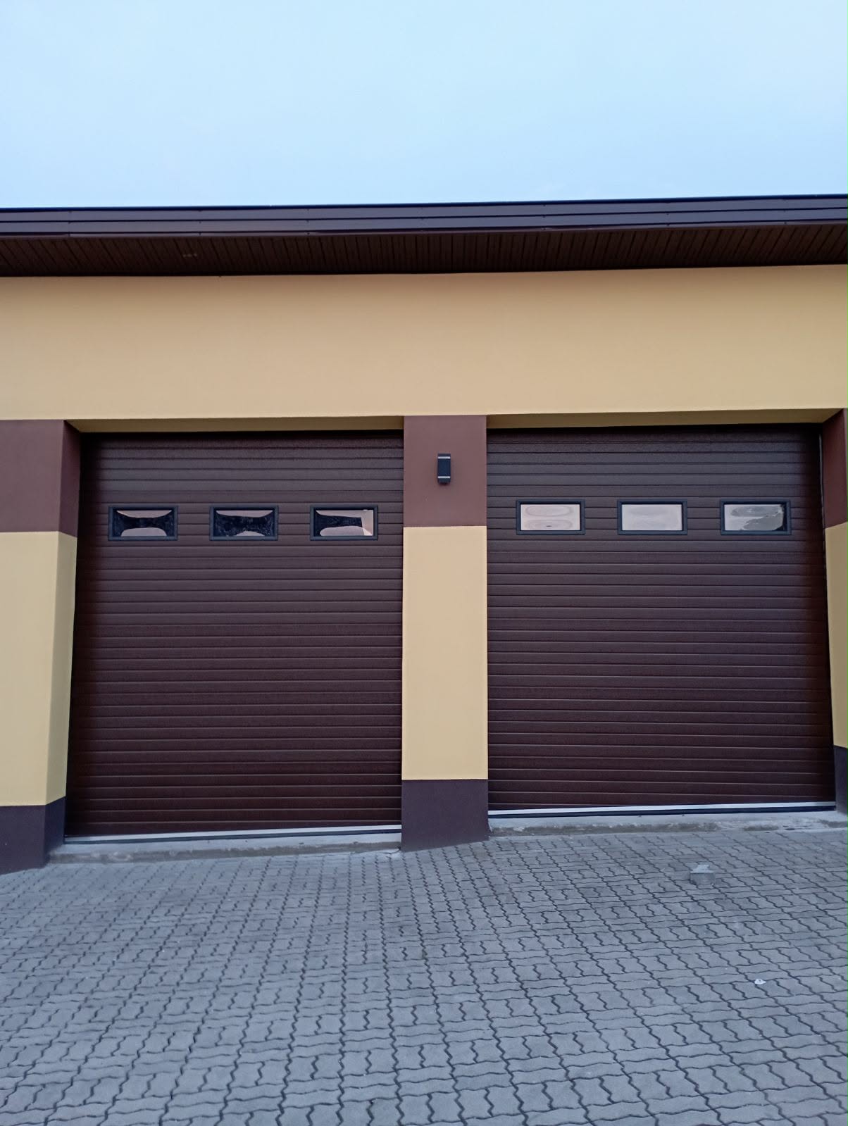 Dwie brązowe bramy z oknami w żółtym budynku