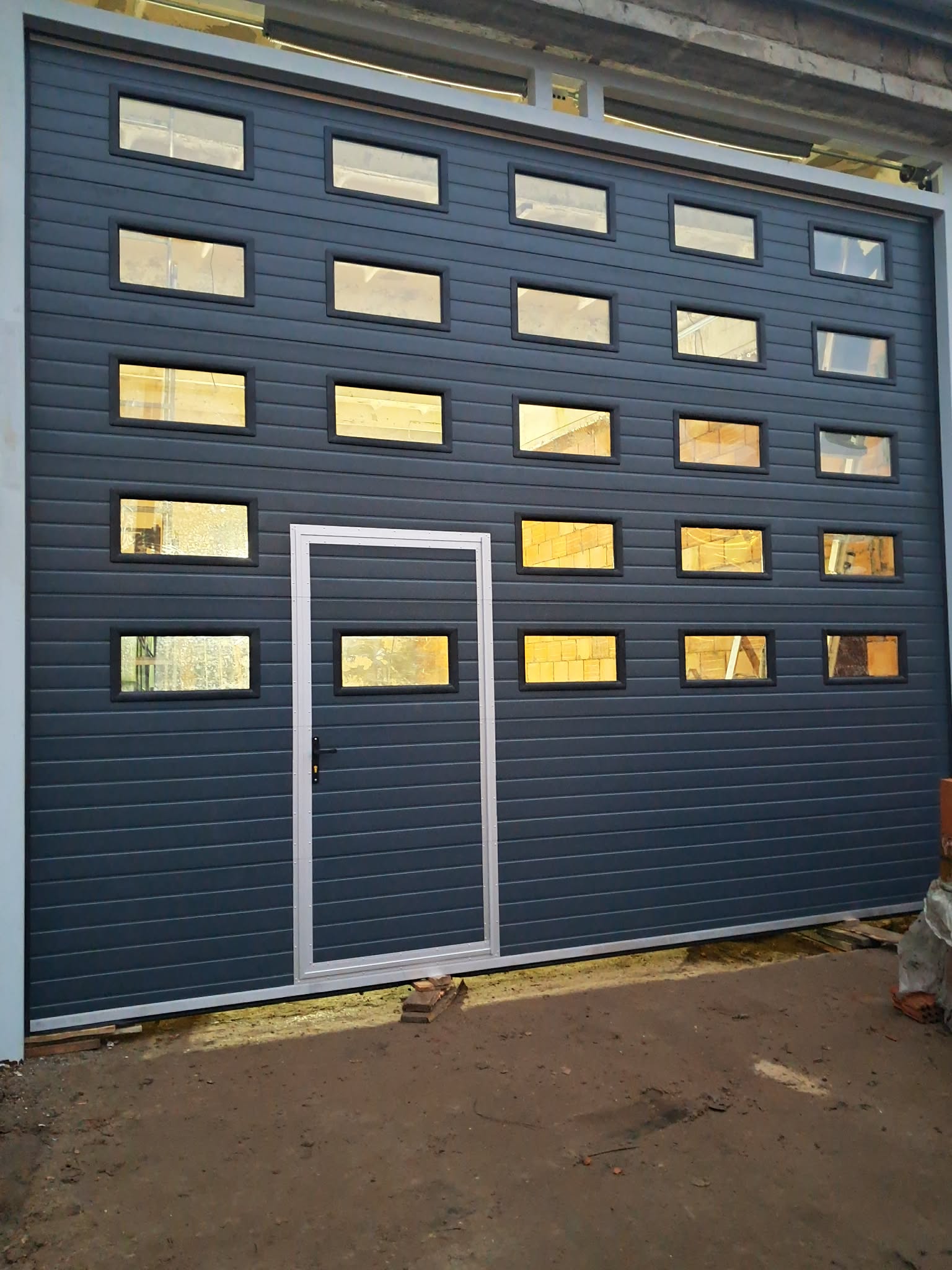 Duża szara brama z wieloma przeszkleniami i drzwiami