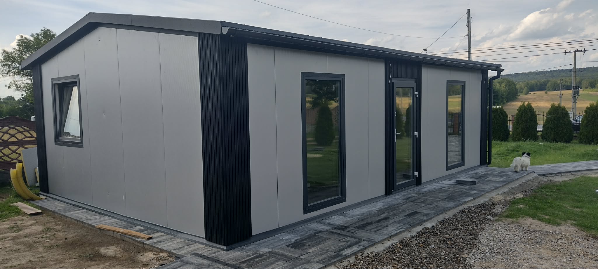 Nowoczesna czarna brama garażowa z oknami w białym garażu